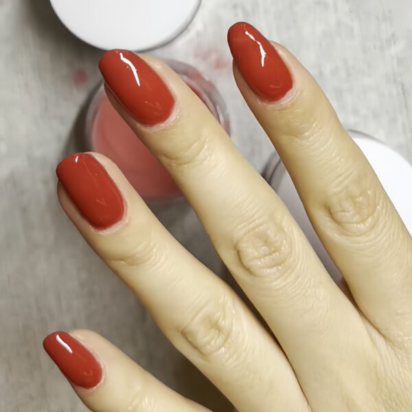 a hand wearing red dip powder nails.